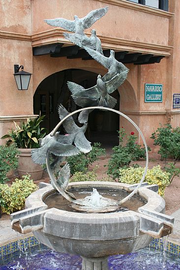 ''FLIGHT OF HOPE'' - Nine life-size doves flying out of a stainless steel ring fountain. by Chris Navarro